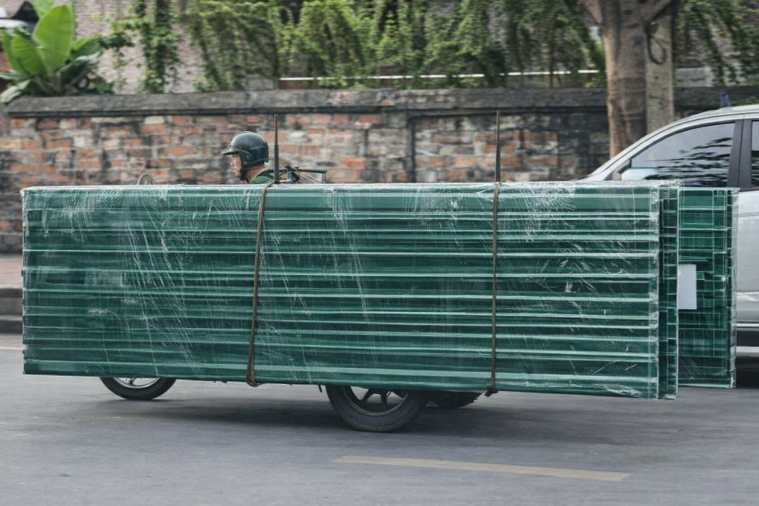 Transport von grünen Wellblech-Baustoffen auf einem Anhänger im Straßenverkehr.