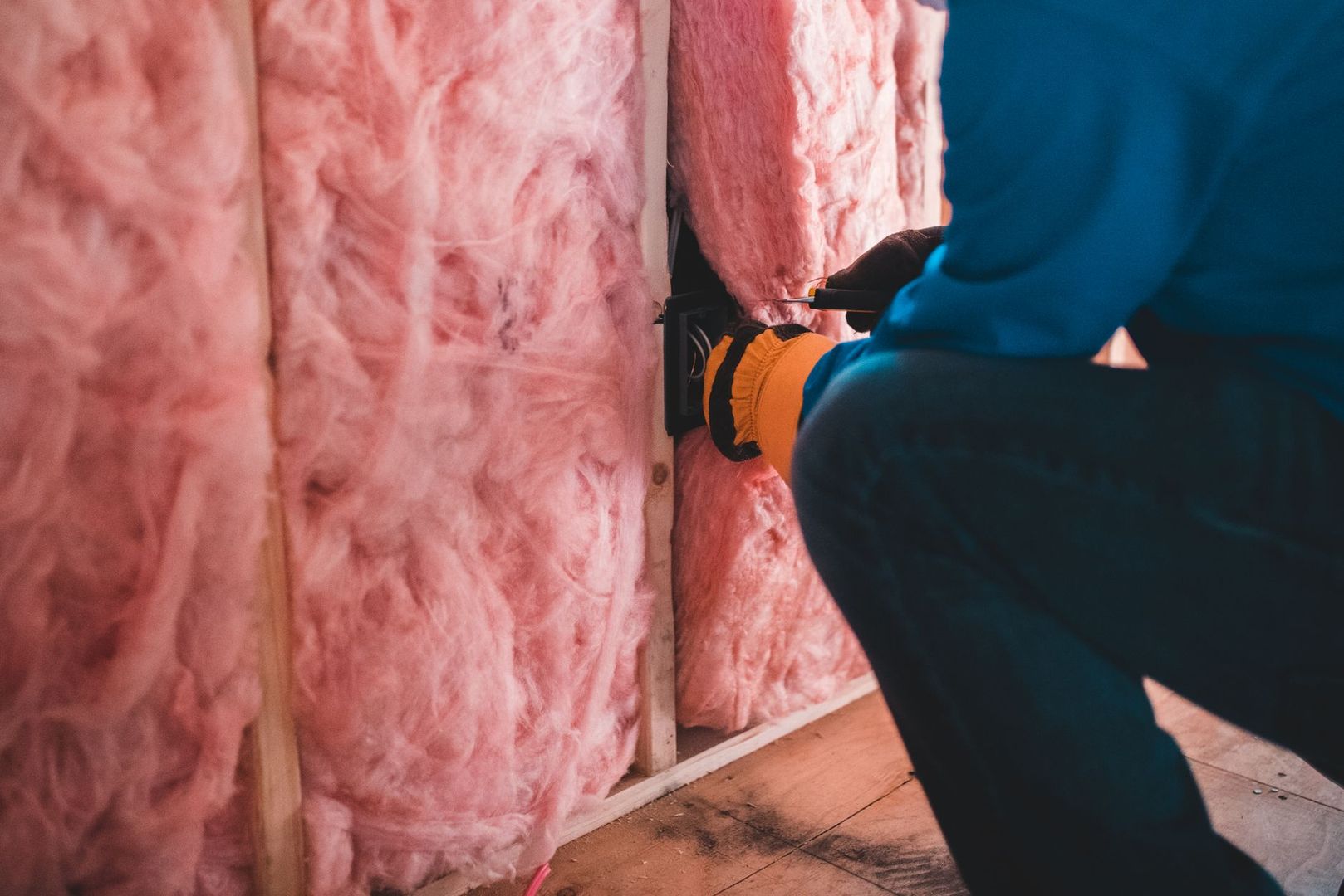 Installation von rosa Dämmmaterial in einer Holzwand.