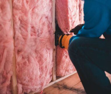 Handwerker bringt Dämmstoff zwischen Holzbalken im Dachausbau an